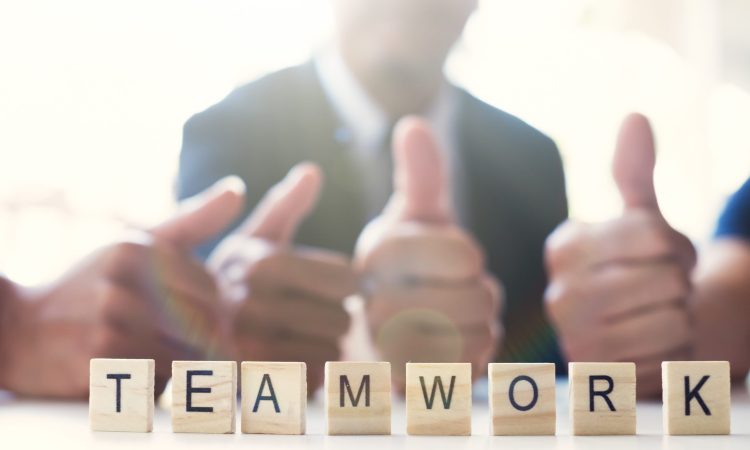 “Teamwork” word on business working table. Wooden cross word alphabet “Teamwork”. Business teamwork concept.